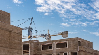 Rohbauarchitektur mit Kränen und blauem Himmel