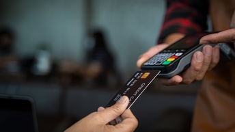 Nahaufnahme von einem Bezahlvorgang mit Händen, die mit Karte an einem EC-Terminal bezahlen