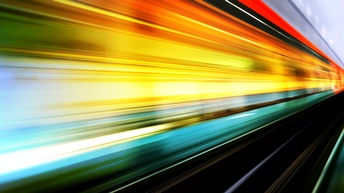 Bewegungsunscharfe Lichtlinien eines Zuges, der auf Schienen fährt.