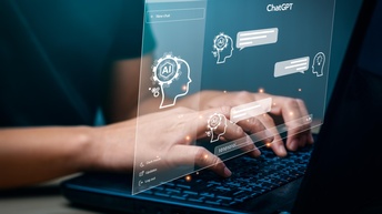 Die Hände einer Person liegen auf der Tastatur eines Laptops. Darüber ist grafisch eine Website gelegt. Innerhalb der Website steht ChatGPT sowie Ai. Außerdem sind darin Sprechblasen