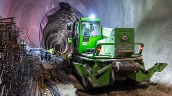 In einem Tunnel steht ein grünes Baufahrzeug. Links daneben sind Metallstäbe