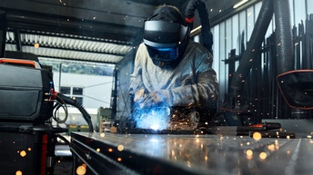 Eine Person in Schutzausrüstung schweißt Platten in einer Werkstatt