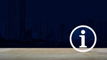 Auf einem Tisch aus braunem Holz  ist das Symbol eines weißen Kreises, in dem der Buchstabe i ist. Der Hintergrund ist schwarz