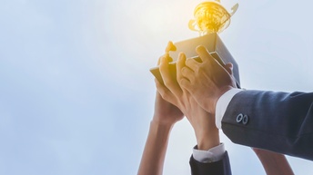Vier Personen halten gemeinsam einen Pokal in die Höhe