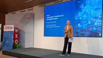 Veranstaltungssaal mit Publikum, am Podium steht Sibylle Regensberger, die Obfrau der Sparte Information und Consulting