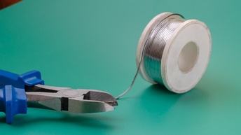 Eine Rolle Draht und links davon eine blaue Zange