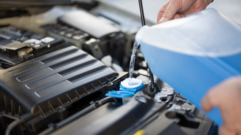 blauer Scheibenfrostschutz wird in Scheibenwaschbehälter eines Autos gefüllt