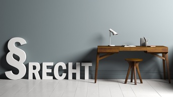 Vektor-Illustration einer grauen Wand, an der ein brauner Schreibtisch mit einem Hocker steht. Auf dem Tisch sind eine Lampe, ein aufgeklapptes Buch und Stifte. Neben dem Tisch sind ein großes weißes Paragrafenzeichen und der Schriftzug des Wortes Recht