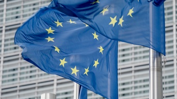 Zwei wehende EU-Flaggen an Fahnenmasten.