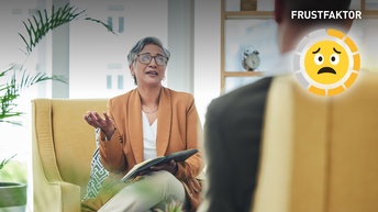 Beratungsgespräch mit Psychologin. Zwei Personen vis-à-vis, sitzend auf einem gelben Sessel.