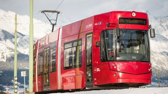 Roter Zug im mVordergrund - im Hintergrund verschneite Berge