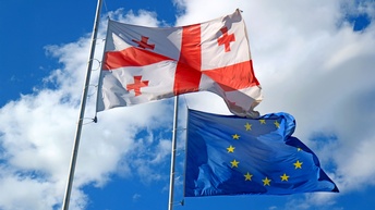 Die Flaggen Georgiens und der EU vor blauem Himmel