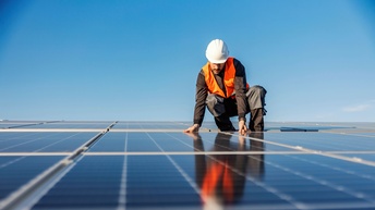 Ein Elektrotechniker bei der Installation von Solar Paneelen