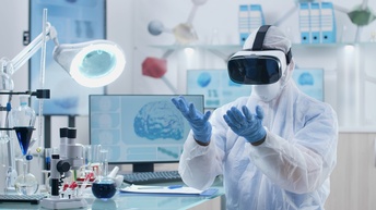 Person mit weißem Schutzanzug, FFP-Maske und blauen Handschuhen trägt eine Virtual Reality Brille und steht dabei in einem Labor