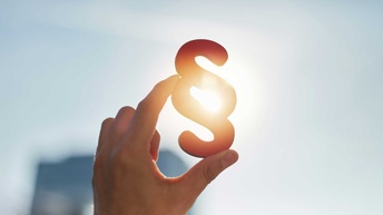 Hand hält Paragraphen Symbol in Sonne 