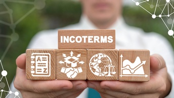 Ein im Hintergrund verschwommener Mann hält Holzwürfel. Auf einem steht Incoterms geschrieben.