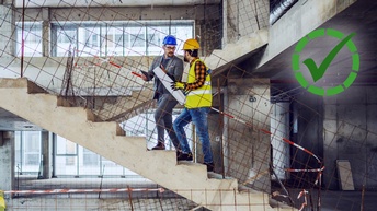 Zwei Fachkräfte mit Helmen besprechen auf einer Baustelle Pläne.
