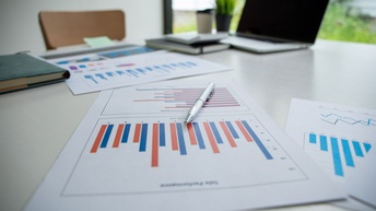 Papierblätter mit farbigen Diagrammen und Grafiken auf einem Schreibtisch