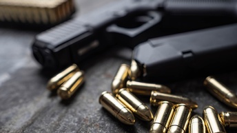 Nahaufnahme einer Pistole mit Munition im Vordergrund