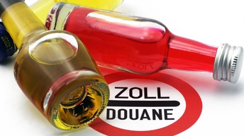 Eine kleine Weißwein- und Rotweinflascche auf einem Zollschild