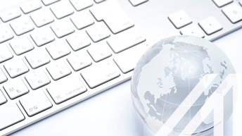 Weiß-silberne Tastatur und Globus aus Glas auf weiß-grauem Untergrund<br />
