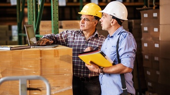 Zwei Männer arbeiten im Zolllager am PC