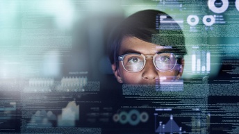 Frontale Aufnahme des Kopfes einer Person mit kurzen, dunklen Haaren. Vor dem Kopf sind die Grafiken von Quellcodes, Statistiken und Diagrammen