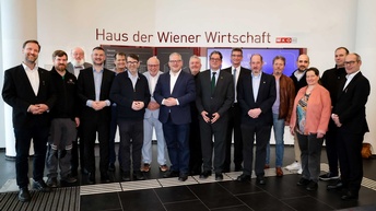 Gruppenfoto des Gremialausschusses des Wiener Computerhandels: Mehrere Personen nebeneinander stehend, im Hintergrund an der Wand der Schriftzug Haus der Wiener Wirtschaft