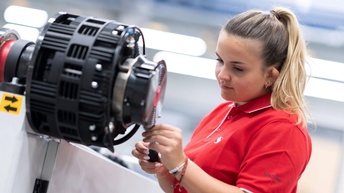 Frau in rotem Poloshirt arbeitet an der Maschine
