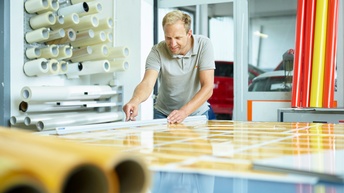 Ein Mann schneidet auf einem Tisch Folien zurecht