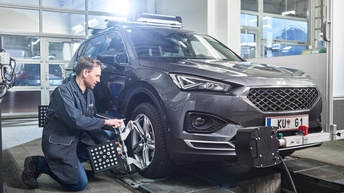Ein junger Mann in der Werkstatt montiert ein Rad an einem großen Wagen