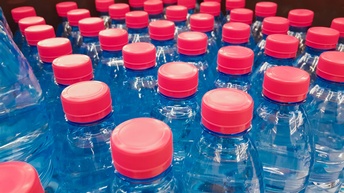 Nahaufnahme von Wasserflaschen aus Plastik mit roten Drehkappen.