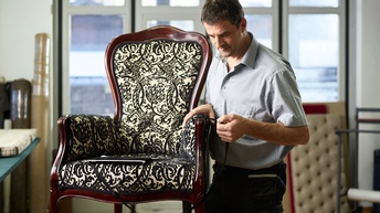 Ein Mann arbeitet an einem schwarz-weiß gemusterten Sessel