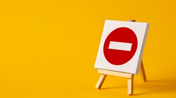 Roter Kreis mit in der Mitte gerade verlaufendem weißen Strich auf weißer Leinwand auf Staffelei stehend vor gelbem Hintergrund