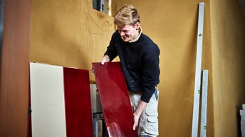 Ein Mann hält eine rote Ofenfliese in der Hand bereit zum Platzieren