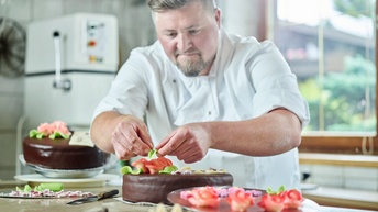Ein Konditor schmückt Schokoladenkuchen mit Marzipanblüten