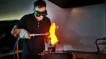 Ein junger Mann gießt geschmolzenes Edelmetall in eine Form