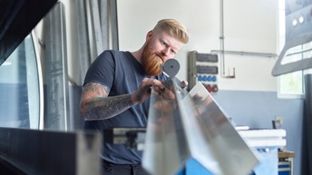 Ein Mann kontrolliert den Winkel eines gefalteten Stahlteiles 