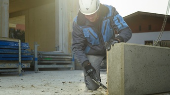 Ein Mann hämmert auf einer Baustelle die Verschalung von einem Betonteil