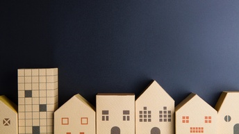 Modelle aus Pappe von verschiedenen Häusern vor einer schwarzen Papierwand