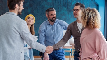 Zwei  von fünf Personen in einer Gruppe reichen sich die Hand