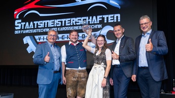 Anna-Maria Bergmann und Leon-Alexander Hobl, die Top 2 der Staatsmeisterschaften für Kraftfahrzeugtechnik, halten den Siegerrpokal in die Höhe. Link zu sehen ist Bundesinnungsmeister Roman Keglovits-Ackerer, rechts im Bild sind Innungsmeister Michael Schnabl