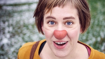 Eine lächelnde Frau mit Clownnase.