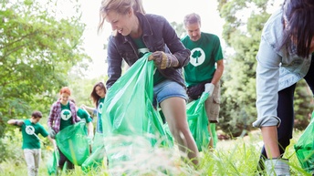 Umweltschützer sammeln Müll auf einer Wiese.