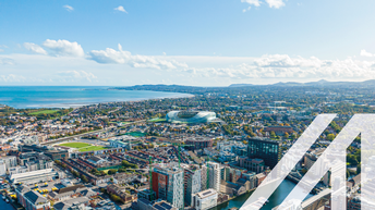 Luftaufnahme von Dublin mit Blick auf den Hafen und moderne Gebäude, im Hintergrund sieht man das Meer und Wolken am Himmel