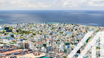 Blick auf den Hafen und die bunte Stadt Male, Hauptstadt der Malediven, mit vielen Hochhäusern vor dem tiefblauen Ozean
