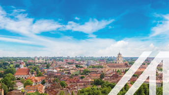 Stadtbild von Vilnius mit vielen Bäumen und roten Häusern, im Hintergrund sieht man eine Kirche