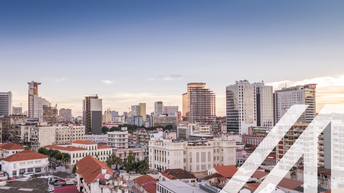 Blick auf Luanda, Hauptstadt von Agola. Man sieht im Vordergrund historische weiße Häuser mit roten Dächern, im Hintergrund Wolkenkratzer.