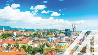 Panoramablick auf die roten Dächer der historischen Häuser im Zentrum von Zagreb mit der katholischen Kathedrale, der Himmel mit einigen Wolken ist blau