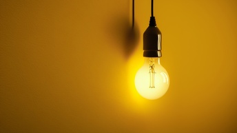 Hell erleuchtete Glühbirne vor einem gelben Hintergrund